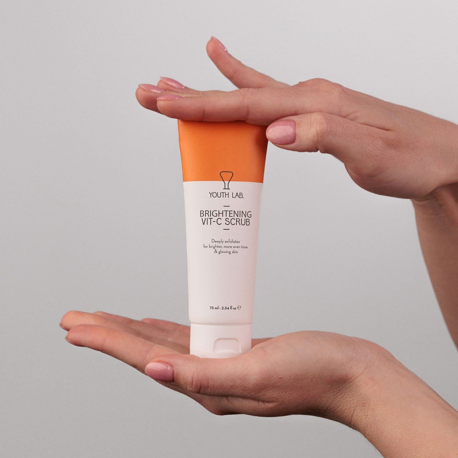 Person holding a tube of South Lab Brightening White Cream against a gray background