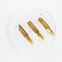 Three amber-colored ampoules on a white background.